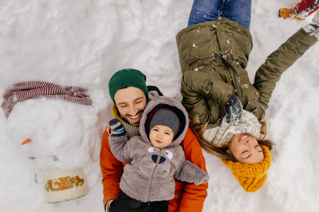 Portrait of a child and his parents proudly posing with a Snowman they have made together